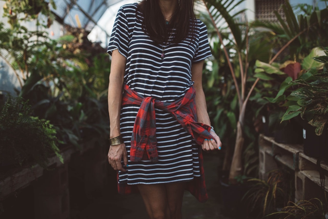 A woman wearing a dress with a flannel wrapped around her waist wears an elastic bracelet. A woman wearing a dress with a flannel wrapped around her waist wears an elastic bracelet.