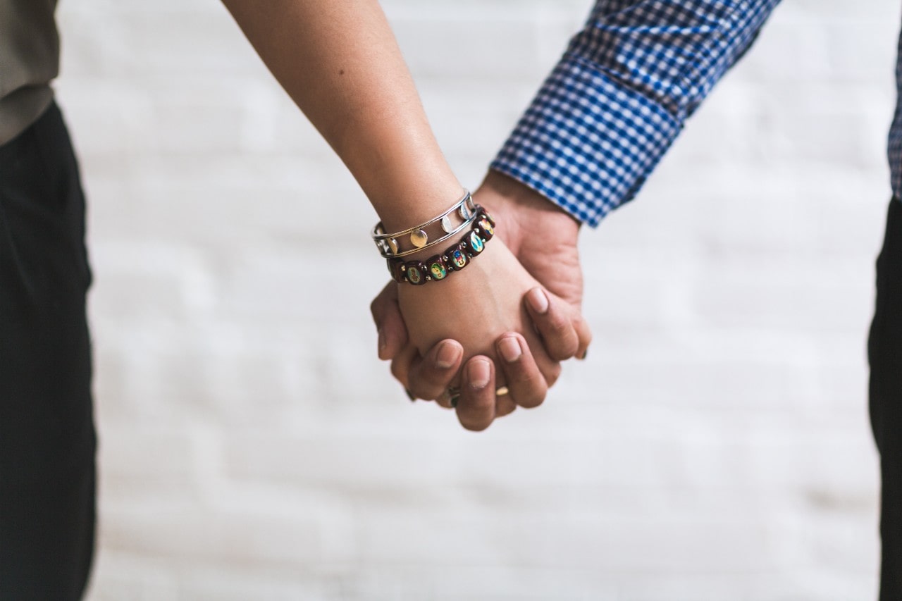 A couple holding hands, the woman wearing a silver bangle and a gemstone bracelet. A couple holding hands, the woman wearing a silver bangle and a gemstone bracelet.